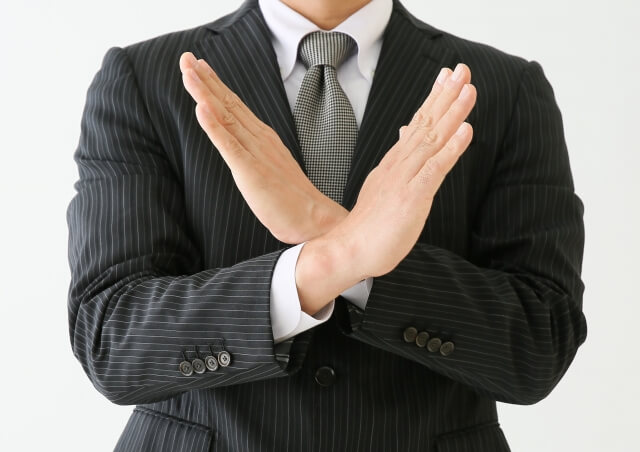 手でバッテンをしている男性